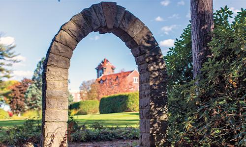 A view of the Alumni Hall bell tower from the monastery graveyard arch