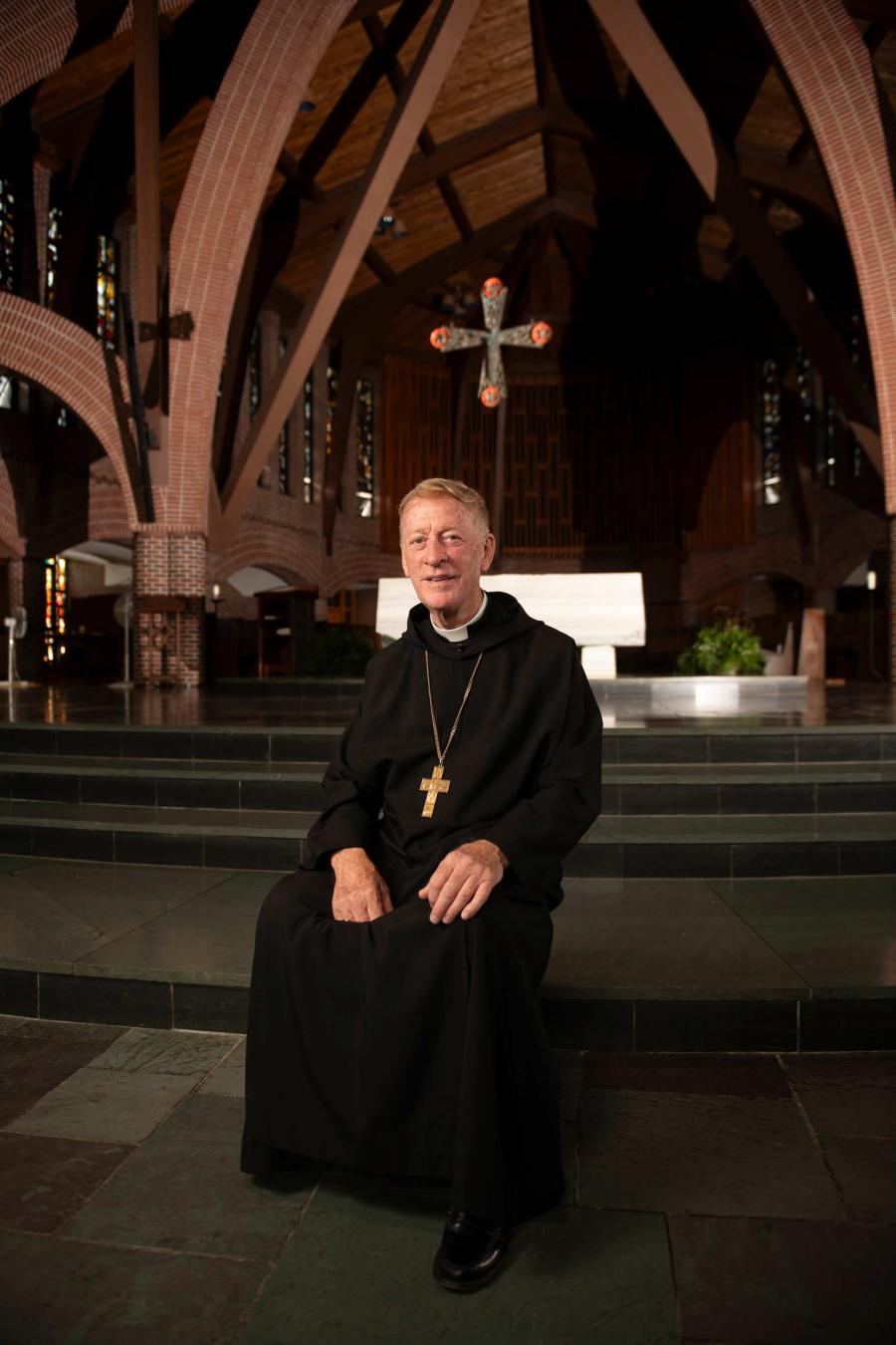 Abbot Mark Cooper, O.S.B. ’71 sitting on the altar steps in the Abbey Church